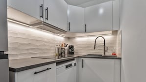 Una cocina moderna con armarios blancos, encimera negra y pileta de acero inoxidable.