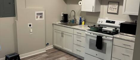 A kitchen with white cabinets, a stainless steel stove, and a wooden floor.