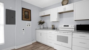 A modern kitchen with white cabinetry, a built-in oven, and a microwave. - Charming 2-bedroom house with AC, WiFi in Columbus (Columbus)