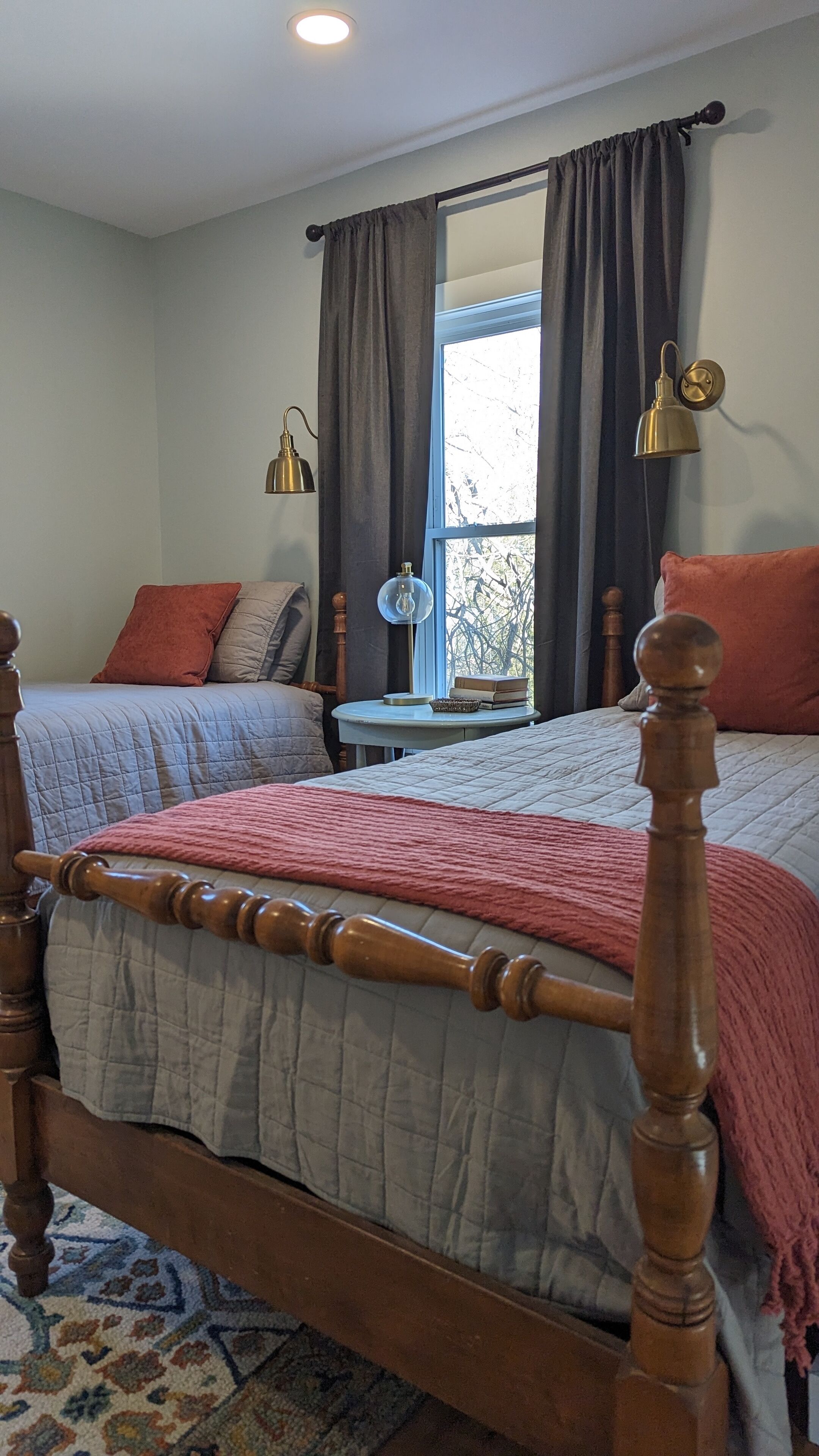 A bedroom with two beds, a small table, and a window with curtains.