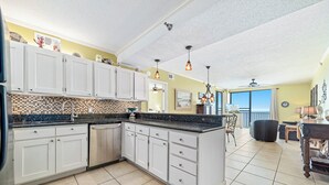 A spacious kitchen with white cabinets, a tiled backsplash, and a large island. - Romar Place 702 | Spectacular Gulf Views Oceanfront Condo | Beach Getaways (Orange Beach)