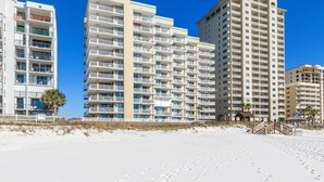 A beachfront hotel with multiple floors, balconies, and a sandy beach in the foreground. - Romar Place 702 | Spectacular Gulf Views Oceanfront Condo | Beach Getaways (Orange Beach)