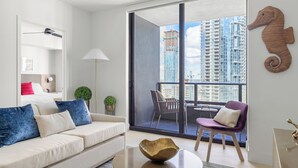A modern living room with a sofa, a coffee table, and a view of a cityscape through large windows. - 2409 - Spacious 1BR w Balcony & Stunning Views - Pool, Gym, Near Arena & Bayside (Miami)