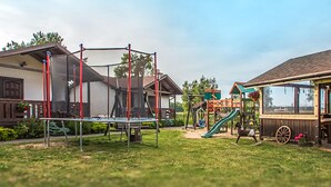 Une aire de jeux avec des balançoires, un toboggan et des structures d’escalade.