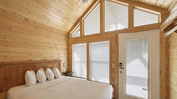 Un dormitorio con paneles de madera, una cama, una mesita de noche y una puerta con ventana.