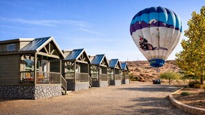 Una fila de cabañas con paneles solares, un globo aerostático al fondo y un paisaje desértico.