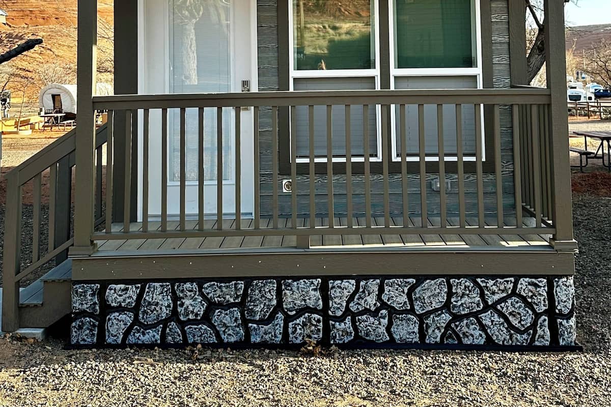 A small cabin with a stone foundation, a wooden porch, and a sign indicating the address 19A.