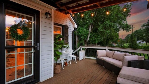 A covered porch with a wooden deck, a white table with chairs, and a cushioned seating area. - Charming 3br Property with fenced in downtown Mooresville, NC (Mooresville)