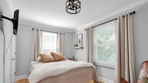A bedroom with a bed, a ceiling light fixture, a window with curtains, and a chair. - Charming 3br Property with fenced in downtown Mooresville, NC (Mooresville)