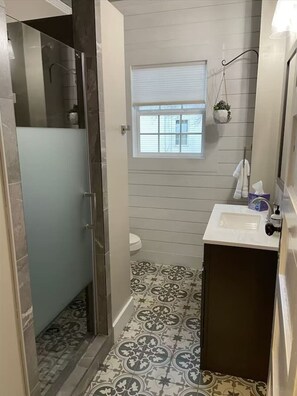 Uma casa de banho com chuveiro, sanita e lavatório.