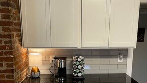 Eine Küche mit weißen Schränken, einer schwarzen Arbeitsplatte, einer Kaffeemaschine und einem dekorativen Behälter.