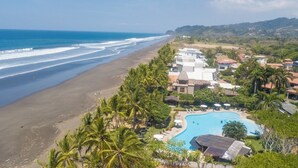 Un resort con vista a la playa, piscina y palmeras.