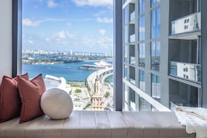 A high-rise hotel room with a large window overlooking a cityscape and water. - 2901 - Beautiful Downtown Apt with Pool and Gym (Miami)