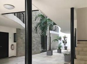 Experience the sleek, modern design of this interior space, featuring a central column, staircase, and fire safety measures.
