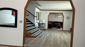 An interior with a wooden staircase leading to a living area, a dining table, and a sofa. - Luxury Estate Accommodations, with a Serene Pool, and Elegant Event Spaces (Douglasville)