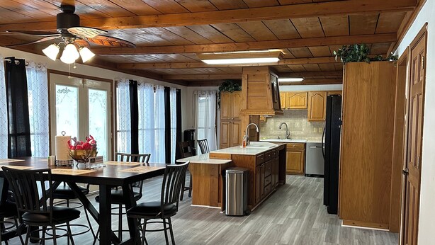 A spacious kitchen with wooden cabinets, a dining area with a table and chairs, and a ceiling fan. - Luxury Estate Accommodations, with a Serene Pool, and Elegant Event Spaces (Douglasville)