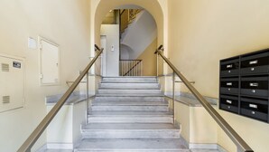 Una escalera con barandillas de metal, un buzón y una puerta con un letrero.