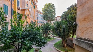 Un patio con un sendero empedrado, rodeado de edificios con balcones y vegetación.