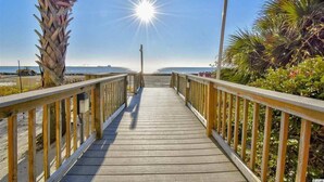 A wooden boardwalk leading to a beach with palm trees and a clear sky. - Romantic Oceanfront 1-Br w/ Balcony (Myrtle Beach)