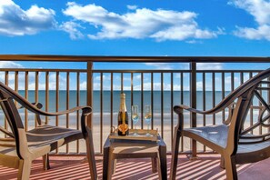 Een balkon met twee stoelen, een tafel en een fles champagne.