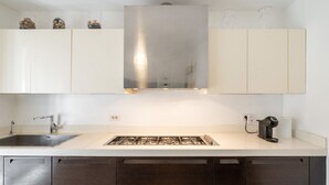 Eine moderne Küche mit weißen Schränken, einer Edelstahl-Dunstabzugshaube, einem Spülbecken und einer Kaffeemaschine.