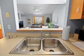 A modern kitchen with a double sink, a ceiling fan, and a view into the living area through a large mirror. - New! Spacious 4 Bed Great for Commuting, Dogs ok (Columbia)