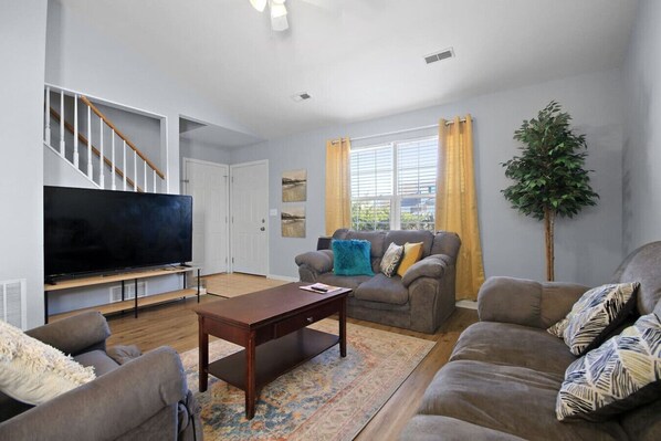 A living room with a flat-screen TV, two sofas, a coffee table, and a staircase. - New! Spacious 4 Bed Great for Commuting, Dogs ok (Columbia)