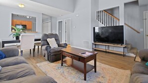 A modern living room with a sofa, armchair, coffee table, and a flat-screen TV. - New! Spacious 4 Bed Great for Commuting, Dogs ok (Columbia)