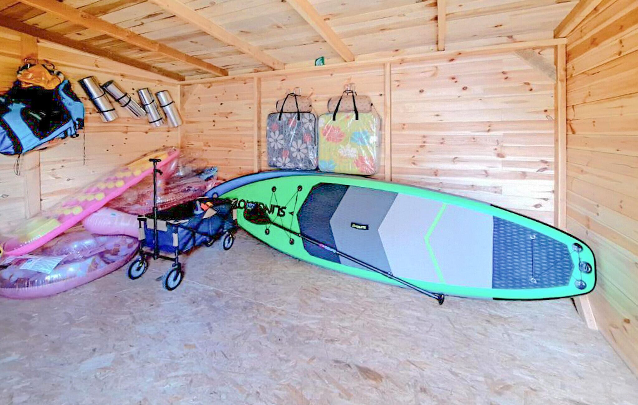 A room with a wooden interior, a green paddleboard, and a stroller.