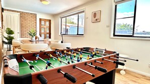 A room with a foosball table, a brick wall, a window, and a door.