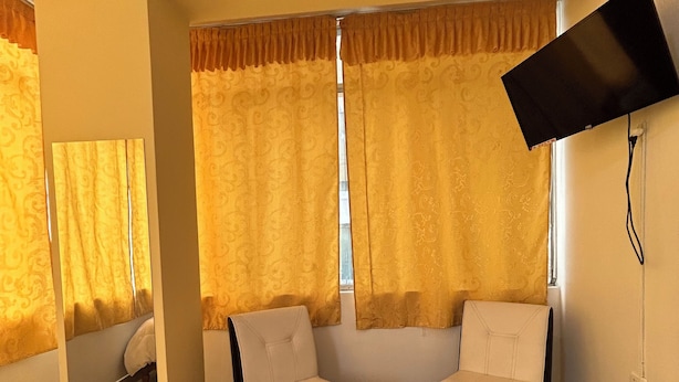 A living room with two white sofas, a black coffee table, and a flat-screen TV mounted on the wall. - Hotel Paraíso L&M (Huánuco)