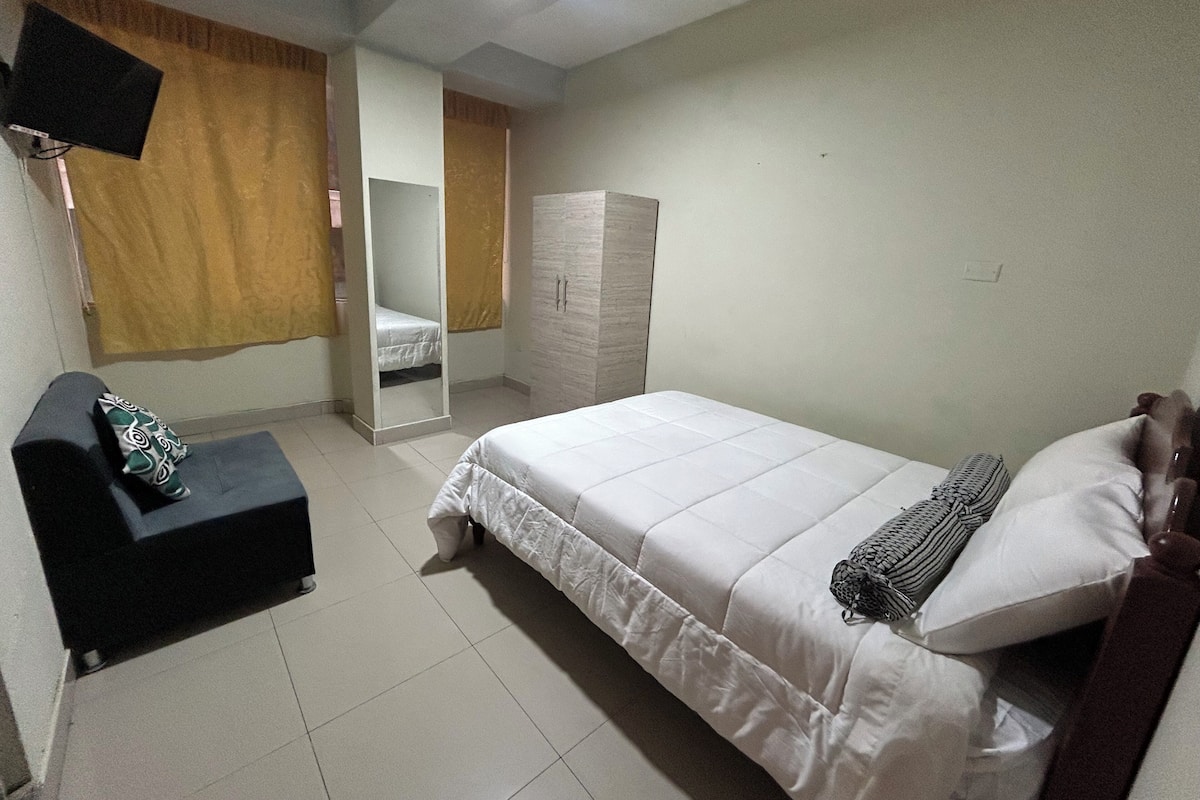 Ein Schlafzimmer mit Bett, Kleiderschrank, Spiegel und Fernseher.
