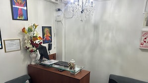 A reception desk with a computer, a telephone, and a vase of flowers. There are two sofas with patterned cushions. - Hotel Paraíso L&M (Huánuco)