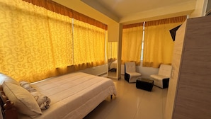 A hotel room with a large bed, a sitting area with a chair and a small table, and a wardrobe. - Hotel Paraíso L&M (Huánuco)