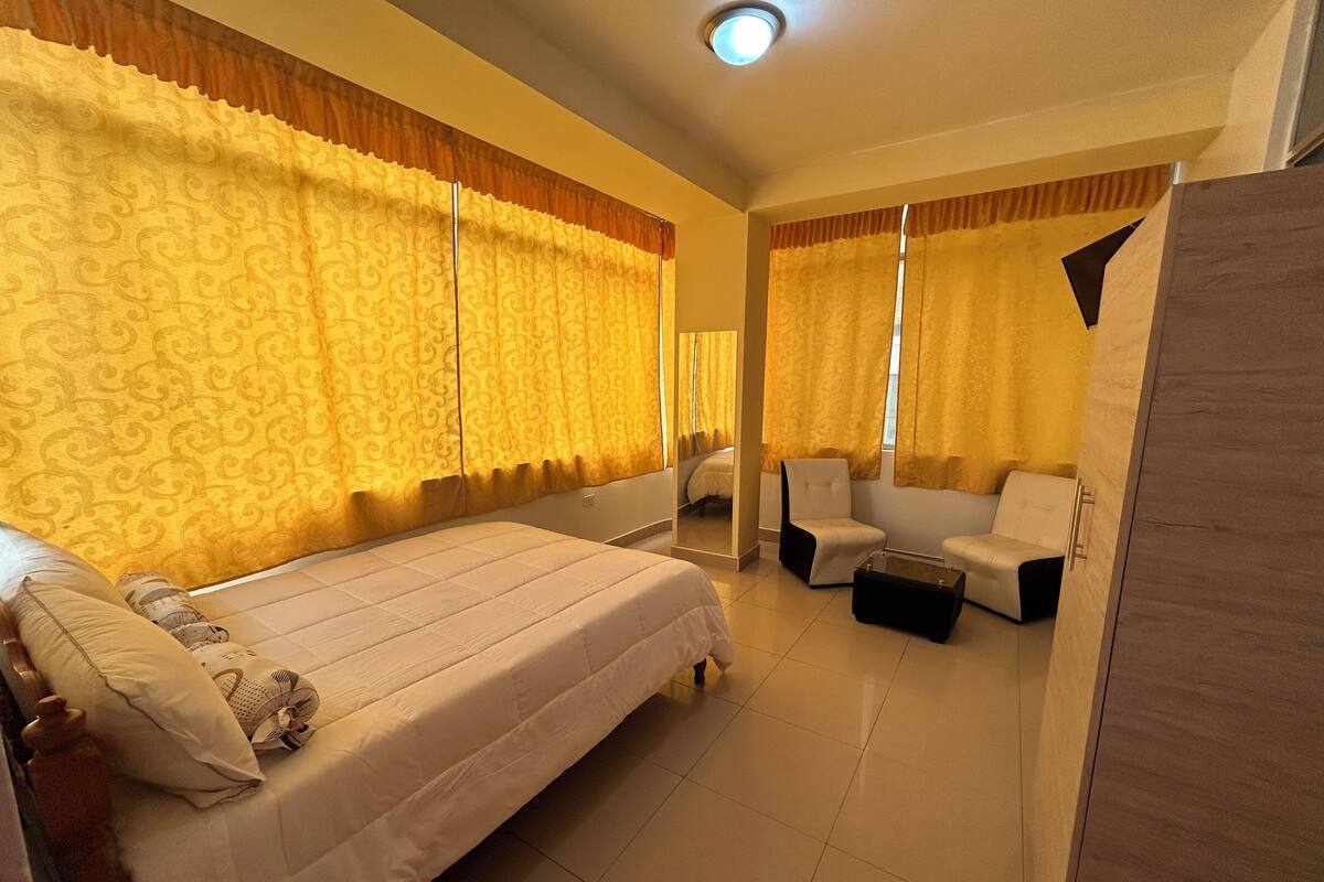 Ein Hotelzimmer mit einem großen Bett, einer Sitzecke mit einem Sessel und einem kleinen Tisch sowie einem Kleiderschrank.