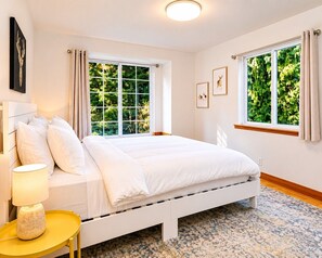 Une chambre à coucher avec un lit, une table de chevet avec une lampe et des fenêtres avec des rideaux.