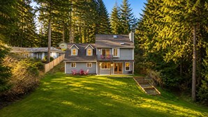 Uma casa de dois andares com varanda, um jardim frontal com deck de madeira e uma pequena área de jardim.