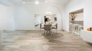 A modern, minimalist living space with a dining area, a kitchen, and a bar area. - Sofia House - City Centre (Cagliari)