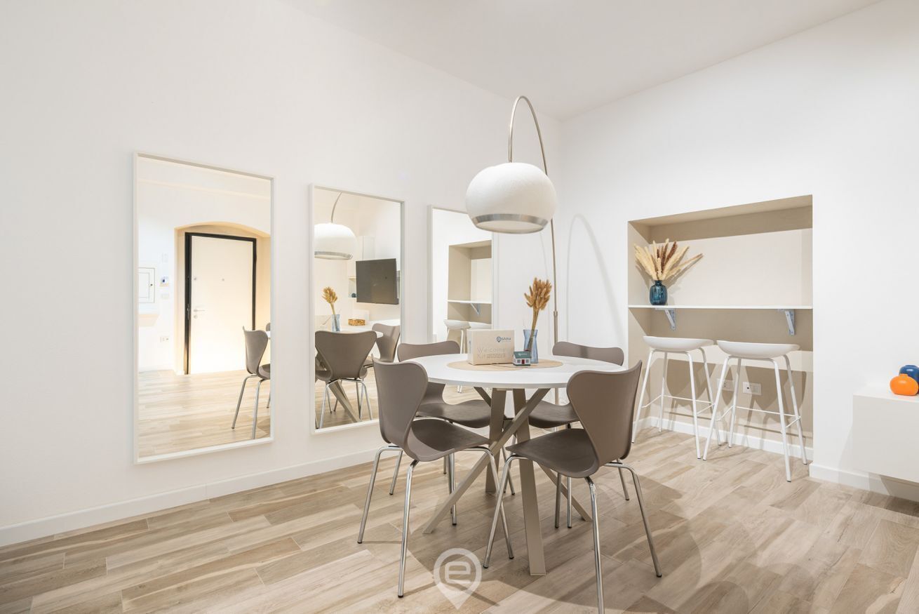 A modern dining area with a round table, chairs, and pendant lighting.