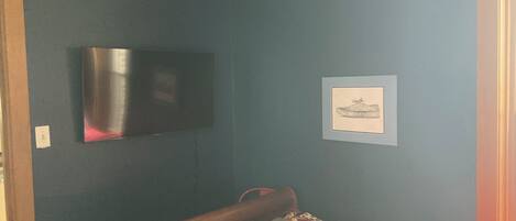 A bedroom with a bed, a television on the wall, and a framed picture.