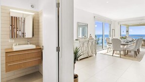 Ein modernes Badezimmer mit Waschtisch, Spiegel und Meerblick durch große Fenster.