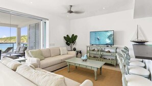 Ein modernes Wohnzimmer mit einer Couch, einem Couchtisch, einem Fernseher und einem Modell eines Segelboots.