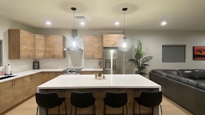Una cocina moderna con una isla central, taburetes de bar y una mesa de comedor.