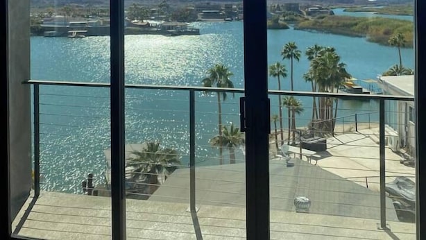 Un amplio ventanal con vistas a un río y montañas.