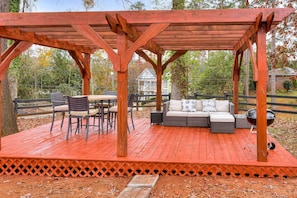 Une terrasse en bois avec une pergola, des meubles d’extérieur et un barbecue.