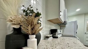 A kitchen with a granite countertop, a coffee machine, and a white refrigerator. - Stylish 2BRM APT: Putting Green: 1mi Masters: 2mi Medical Center (Augusta)