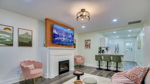 A modern living room with a fireplace, a television, and a kitchen area in the background. - Stylish 2BRM APT: Putting Green: 1mi Masters: 2mi Medical Center (Augusta)