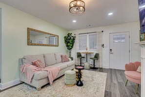 Un salon comprenant un canapé, deux fauteuils, une table basse, un tapis et un miroir accroché au mur.