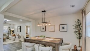 A dining area with a wooden table, six chairs, and a chandelier. - Organic Modern Apt: 1mi to Masters with Pool Table (Augusta)