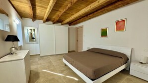 Un dormitori amb un llit, escriptori, armari i mirall.